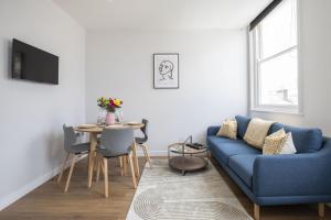 sala de estar con sofá azul y mesa en Beautifully presented newly renovated city-centre apartment in Cheltenham, en Cheltenham