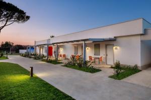 a white building with orange chairs in a yard at Mia Resort Paestum in Paestum