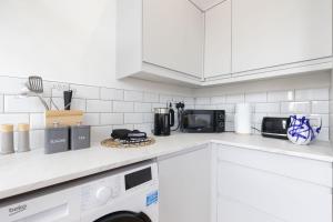 a white kitchen with a microwave and a dishwasher at Beautifully presented newly renovated city-centre apartment in Cheltenham in Cheltenham