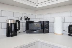 a kitchen counter with a microwave and a coffee maker at Beautifully presented newly renovated city-centre apartment in Cheltenham in Cheltenham +19 photos