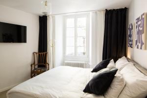 a bedroom with a white bed with black pillows at Marché 28 Guesthouse in Montreux