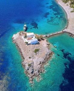 a small island with a boat in the water at Symi . VILLA CALME (Sur la Mer). in Symi