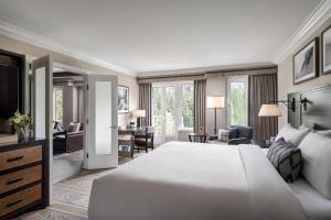 a bedroom with a large white bed and a living room at Fairmont Chateau Whistler in Whistler