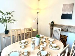 a wooden table with plates and cups on it at Spacious 3 Bedroom House - Sleeps 5 in Manchester