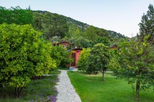 a path in a garden with a red house and trees at Simurg Evleri Olympos in Olympos