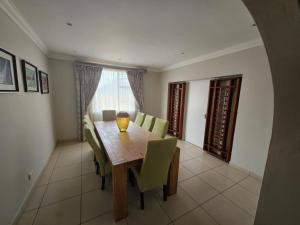 une salle à manger avec une table en bois et des chaises vertes dans l'établissement Ridge Guest House, à Durban