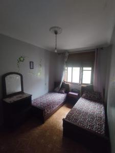 アル・ジャディーダにあるMaison en lieu calmeのベッド3台と窓が備わる客室です。