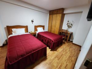 Habitación de hotel con 2 camas con sábanas rojas en Hotel Oceano Mit en Tacna