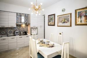 a kitchen with a white table with chairs and a chandelier at Zeus in San Giorgio Ionico