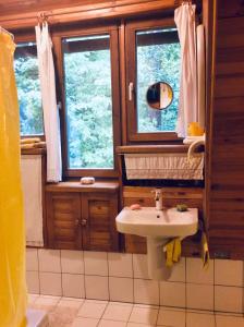 a bathroom with a sink and two windows at Pokój w domu z ogrodem w Milanówku in Milanówek