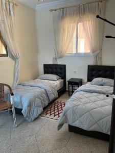 a bedroom with two beds and a window at Hôtel Titrit in Tafraout +7 photos
