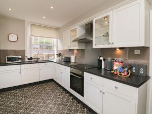 a kitchen with white cabinets and a black counter top at The Outlook in Minehead