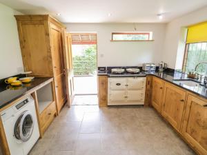 a kitchen with wooden cabinets and a washer and dryer at Hillcroft in Kenilworth