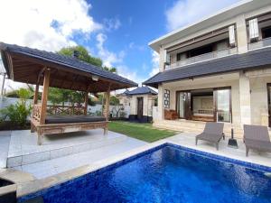 a house with a swimming pool and a pavilion at Villa DiKebun in Uluwatu
