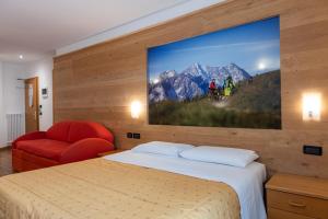 Habitación de hotel con cama y TV en la pared en Sport Hotel Stella Alpina, en Cogolo