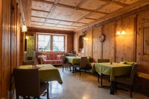 restauracja ze stołami i krzesłami w pokoju z drewnianymi ścianami w obiekcie Sport Hotel Stella Alpina w mieście Cogolo