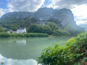 a house on a river with a mountain in the background at Au Château Saint Blaise in Virignin