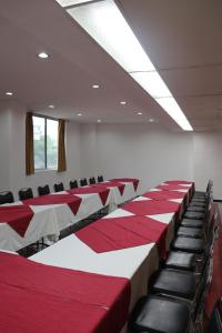 una sala de conferencias con mesas y sillas rojas y blancas en Hotel Calvete en Torreón