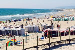 a beach with many people and tents and the ocean at Avenida House a 700 metros da praia in Esposende