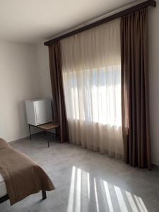 a bedroom with a bed and a window with curtains at NorDar in Garni
