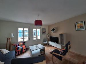 ein Wohnzimmer mit Sofa, Sesseln und Fernseher in der Unterkunft Maison de centre-ville avec grande terrasse in Concarneau