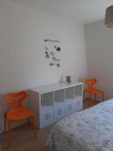 コンカルノーにあるMaison de centre-ville avec grande terrasseのベッドルーム1室(オレンジ色の椅子2脚、白いキャビネット付)
