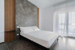 una camera da letto con un grande letto bianco con una grande finestra di Hotel Mhami a Pulsano