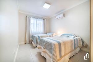 2 camas en una habitación con ventana en Kremer Residence - Apartamento 302: Com todos os ambientes climatizados, en Bombinhas