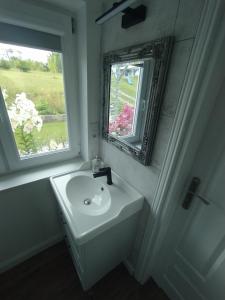 a white bathroom with a sink and a mirror at Domek letniskowy in Kolno