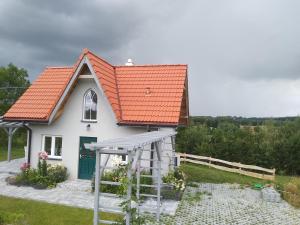 een klein wit huis met een oranje dak bij Domek letniskowy in Kolno