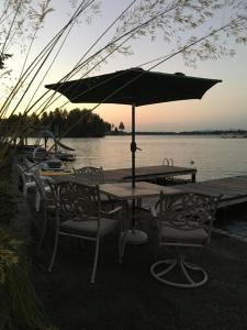 a table and chairs with an umbrella next to the water at Lakefront retreat house in Sumner