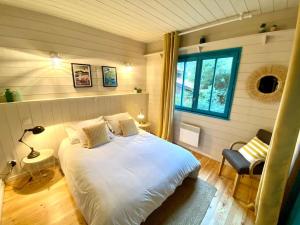 1 dormitorio con cama blanca y ventana en La Maison Bleue, en Cap-Ferret