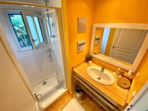 a bathroom with a sink and a shower and a mirror at La Maison Bleue in Cap-Ferret