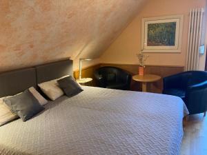 een slaapkamer met een bed met 2 kussens en 2 stoelen bij Ferienwohnung auf dem Eltenberg in Elten