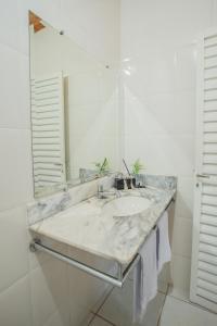 Baño blanco con lavabo y espejo en Recanto das Bromelias, en Brumadinho
