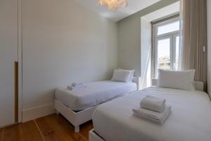 two beds in a room with a window at Liberdade Concept 2BDR Apartment by LovelyStay in Lisbon