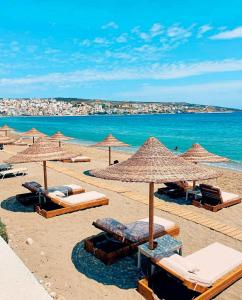 einen Strand mit Liegestühlen und Sonnenschirmen und dem Meer in der Unterkunft Stone House in Sitia