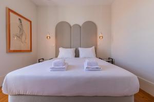 1 cama blanca grande con 2 toallas encima en Liberdade Concept 2BDR Apartment by LovelyStay en Lisboa