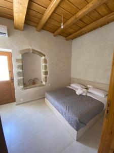 een slaapkamer met een bed en een spiegel aan de muur bij Avli House Vori in Vóroi
