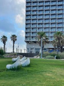 a sculpture in a park in front of a large building at Luxury units by Hilton beach in Tel Aviv
