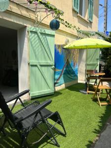 eine Terrasse mit grüner Tür, Stühlen und einem Sonnenschirm in der Unterkunft Beautiful studio + large terrace near the beaches. in Antibes