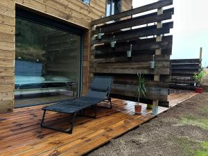 a chair sitting on a deck next to a building at Jardin de l'ancienne école avec Jacuzzi privé in Gérardmer