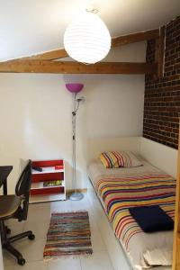 1 dormitorio con cama, escritorio y lámpara en Gîte au cœur d'une résidence d'artiste en Saint-Aubin-de-Bonneval
