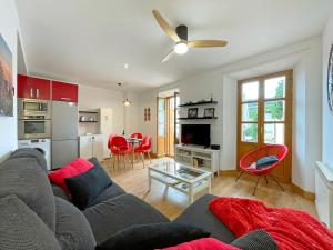 - un salon avec un canapé gris et des fauteuils rouges dans l'établissement Apartamentos Puente La Reina, à Puente la Reina