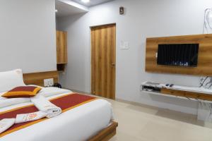 a bedroom with a bed and a tv on a wall at Coco Palms Inn in Alibaug