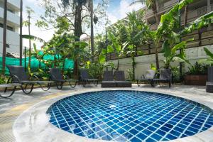 a swimming pool with chairs and a building at Patong Central Hotel & Apartment in Patong Beach