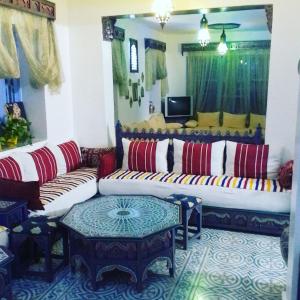 a living room with two couches and a tv at Hôtel Al Kalaa in Chefchaouene
