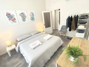 a white bedroom with a large bed and a table at KATUA Cozy Apartment - close to the downtown in Pavia