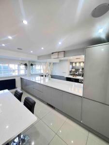 a large kitchen with white counters and tables and chairs at Stunning Home in Astley in Tyldesley