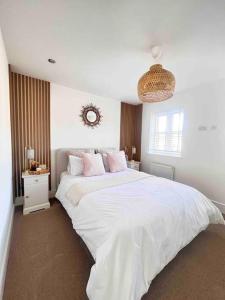 a bedroom with a large white bed with pink pillows at Stunning Home in Astley in Tyldesley